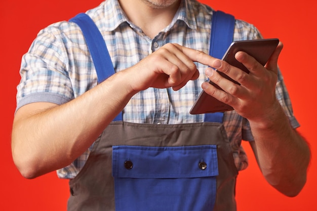 Close-up van een man in overall en een geruit hemd met behulp van een digitale tablet