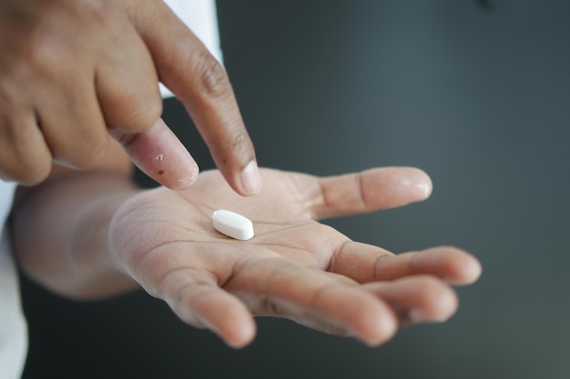 Close-up van een man met een hand die een capsule vasthoudt tegen een zwarte achtergrond