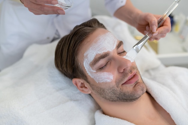 Close-up van een man met een hydraterend masker op zijn gezicht