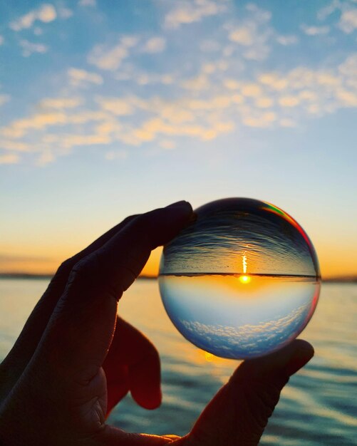 Foto close-up van een man met een kristallen bol tegen de hemel bij zonsondergang