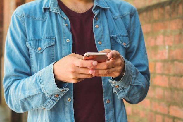 Close-up van een man met zijn mobiele telefoon.