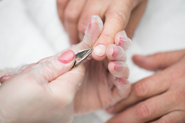 Close-up van een manicure die de cuticula van de vingers van de persoon afsnijdt