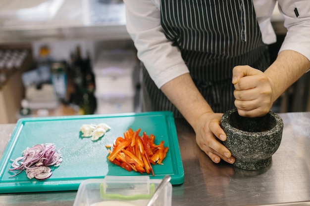 Close-up van een mannelijke chef-kok die knoflooksaus voorbereidt voor een restaurant