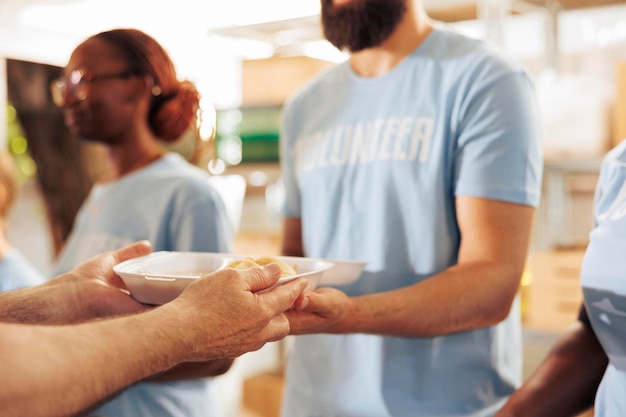 Foto close-up van een mannelijke liefdadigheidswerker die gratis voedsel uitdeelt aan de armen en daklozen. vrijwilliger met een maaltijddoos om te geven aan de hongerigen en minder fortuinlijke bij een buitenvoedselbank.