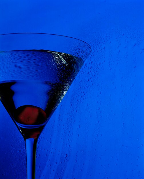 Foto close-up van een martini glas tegen een blauwe achtergrond