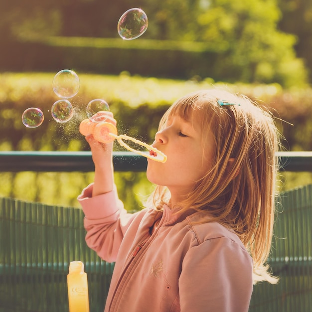 Close-up van een meisje dat bubbels blaast in het park.