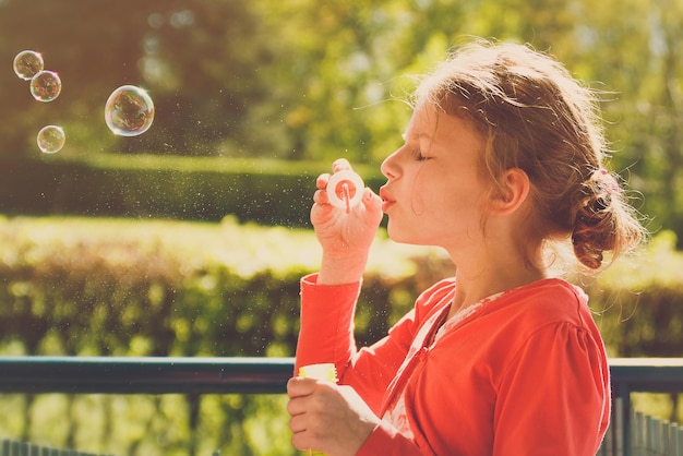 Close-up van een meisje dat bubbels blaast in het park.