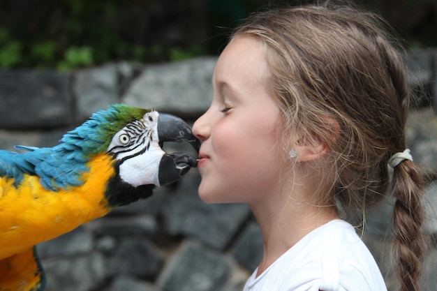 Foto close-up van een meisje dat een ara zoent.