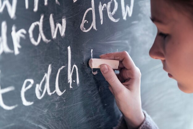 Close-up van een meisje dat op het bord schrijft in de klas.