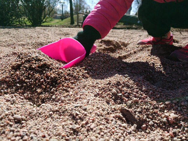 Foto close-up van een meisje dat zand plukt met een schaal op de speeltuin