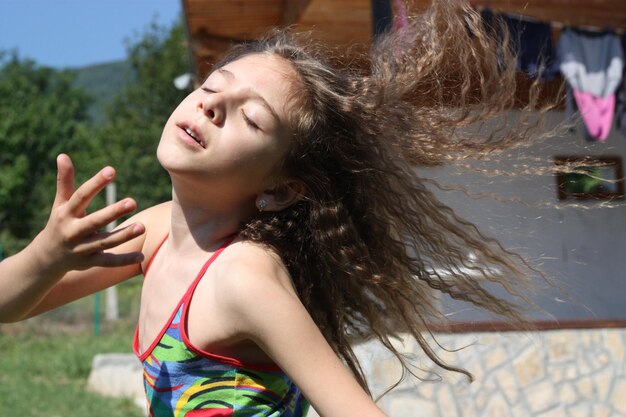 Foto close-up van een meisje met verward haar dat tegen het huis staat