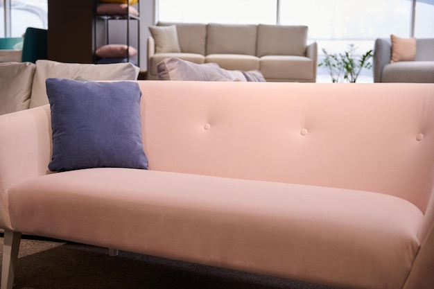 Close-up van een moderne, stijlvolle roze bank met een paars kussen in een meubelshowroom die te koop wordt aangeboden