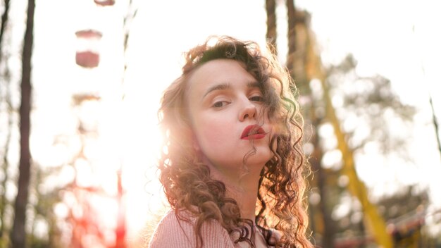 Close-up van een mooie jonge vrouw met krullend haar - een zonsondergang achter haar