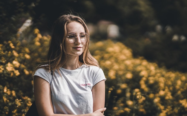 Close-up van een mooie vrouw die tegen gele bloemen staat