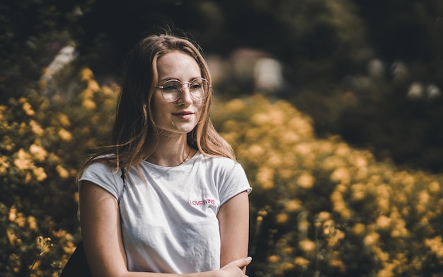 Foto close-up van een mooie vrouw die tegen gele bloemen staat