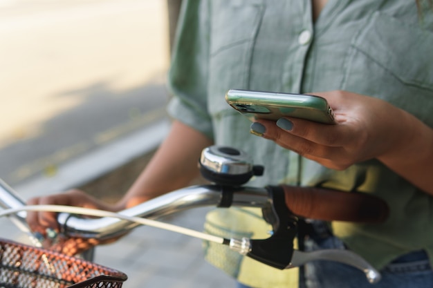 Close-up van een onherkenbare vrouw die haar slimme telefoon op een fiets gebruikt