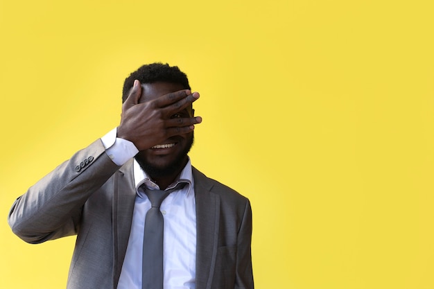 Close-up van een ontevreden afro Amerikaanse man met hand op hoofd puffend in studio gele achtergrond