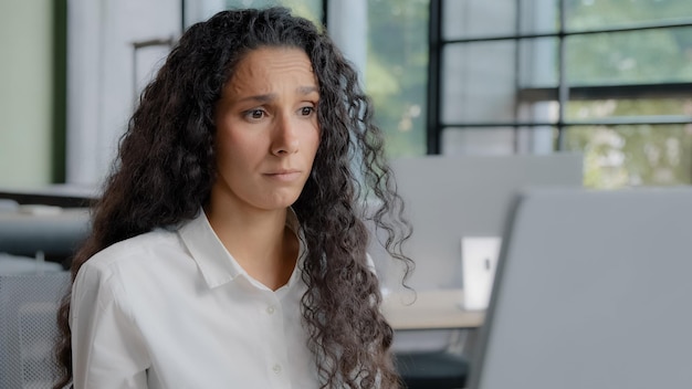 Close-up van een opgewonden jonge vrouw die naar een computerscherm kijkt en slecht nieuws leest.