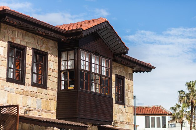 Close-up van een oud stenen gebouw met een houten balkon en ramen