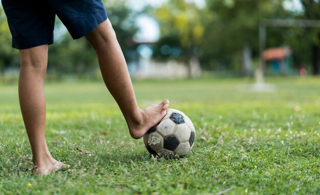 Close-up van een oude voetbaljongen die geen schoenen draagt en klaar is om de bal op het oude voetbalveld te schoppen