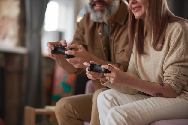 Close-up van een paar dat joysticks gebruikt en online videogames speelt op de bank in de kamer