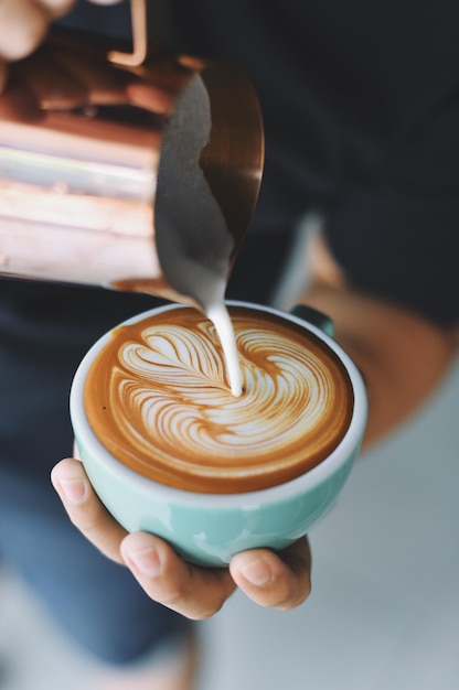 Close-up van een persoon die cappuccino bereidt