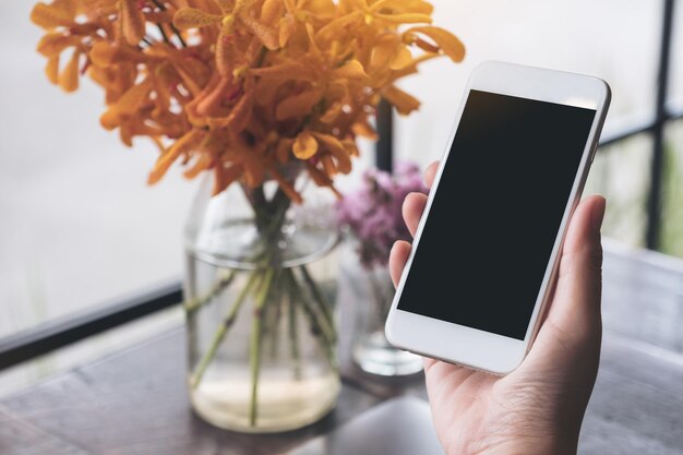 Foto close-up van een persoon die een mobiele telefoon gebruikt in een café