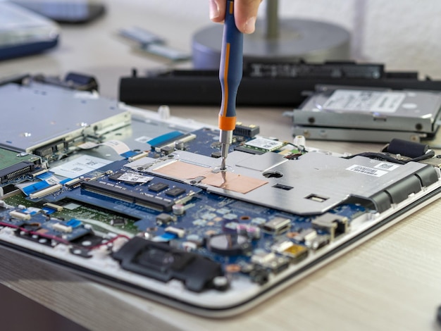 Close-up van een persoon die een tablet met een schroevendraaier repareert