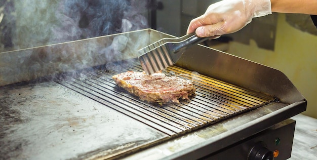 Close-up van een persoon die eten bereidt op een barbecue grill