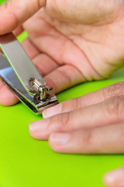 Foto close-up van een persoon die nagels snijdt op een groene achtergrond