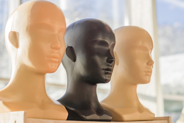 Foto close-up van een plastic vrouw mannequin hoofden op houten rack