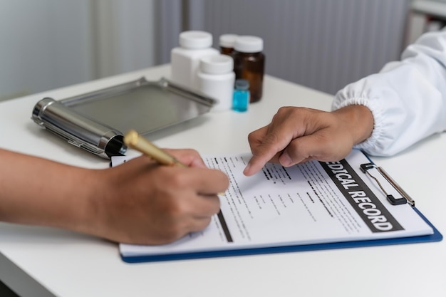 Foto close-up van een professionele arts en een patiënt die een medische verzekeringspolis ondertekenen. de arts neemt nota van het papierwerk voor de gezondheidszorg