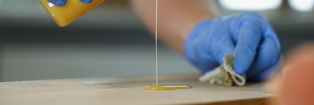 Close-up van een reparateur die een houten balk vernist die werkt bij een reparatiewerkman die speciaal toepast