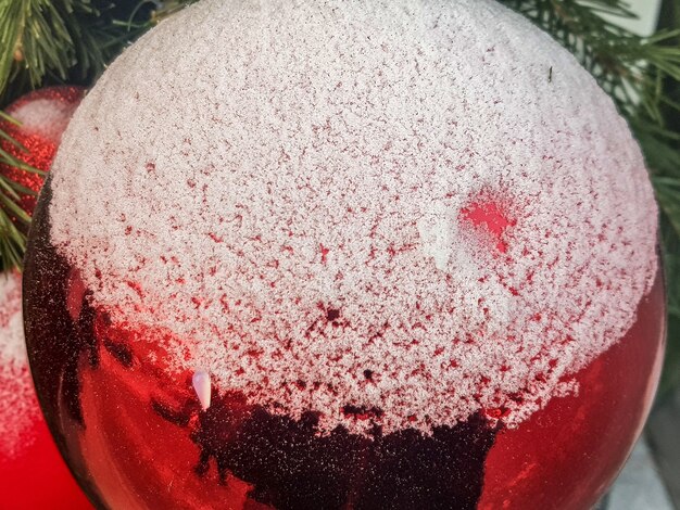 Close-up van een rode glanzende kerstbal bedekt met sneeuw, het concept van een feestelijke decoratie en achtergrond.