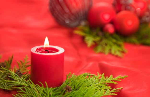 Close-up van een rood aangestoken kaars met kerstversieringen