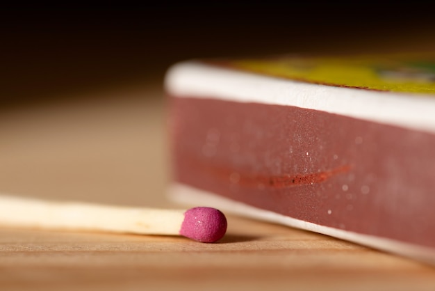 Close-up van een roze lucifer die op tafel bij de luciferdoos ligt