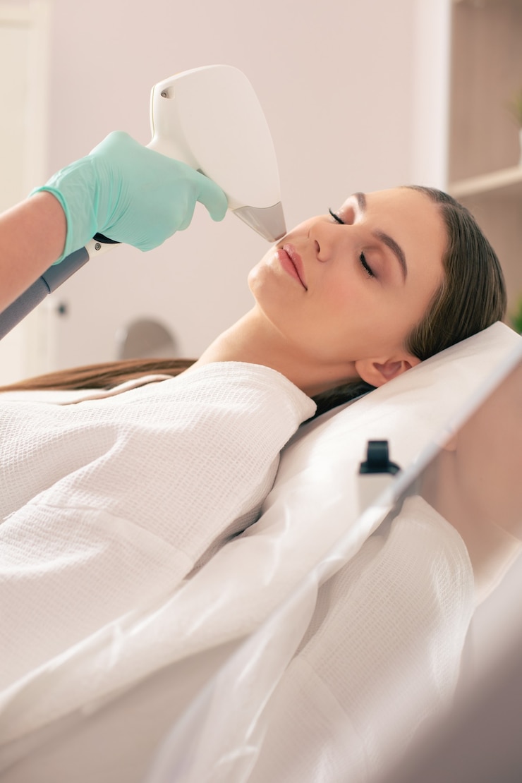 Close-up van een rustige vrouw die haar ogen gesloten heeft terwijl ze in de schoonheidssalon is en de procedure van laserontharing op haar gezicht heeft