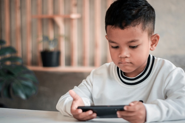 Close-up van een schattig klein 4s blank jongenskind, kijk naar het scherm van de mobiele telefoon, speel online spel op gadget.