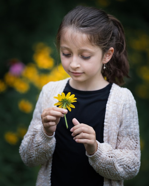 Foto close-up van een schattig meisje met een gele bloem.