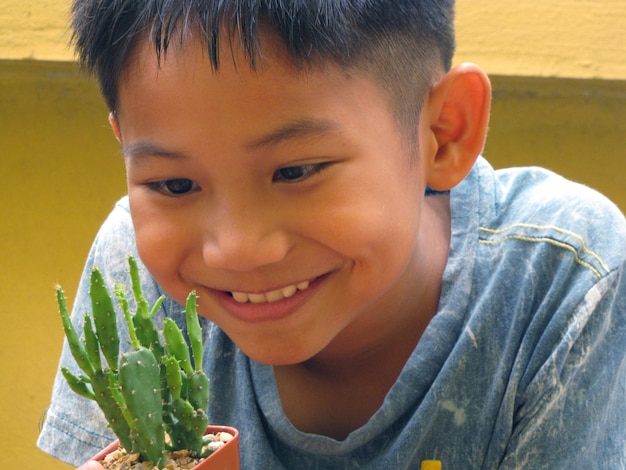 Foto close-up van een schattige jongen die naar een cactus kijkt.