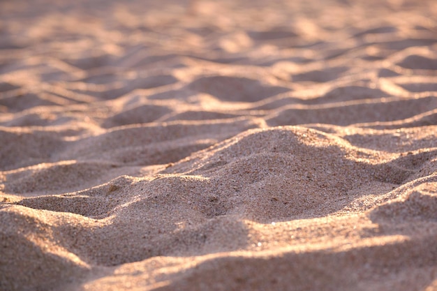 Close-up van een schoon geel zandoppervlak dat het strand aan zee bedekt, verlicht met avondlicht. Reis- en vakantieconcept