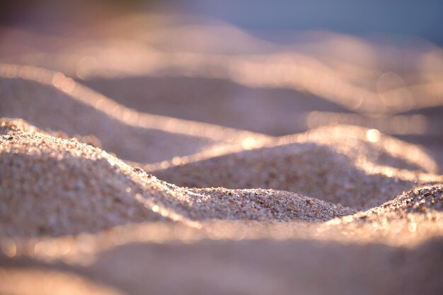 Close-up van een schoon geel zandoppervlak dat het strand aan zee bedekt, verlicht met avondlicht. Reis- en vakantieconcept