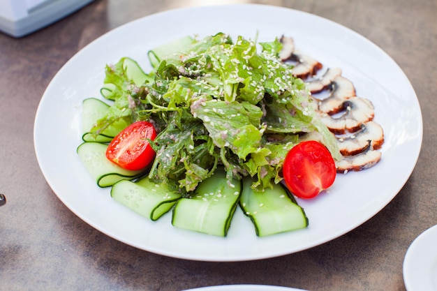 Close-up van een smakelijke verse palingsalade met rucola, sla en tomaten op witte plaat. Gezond eetconcept