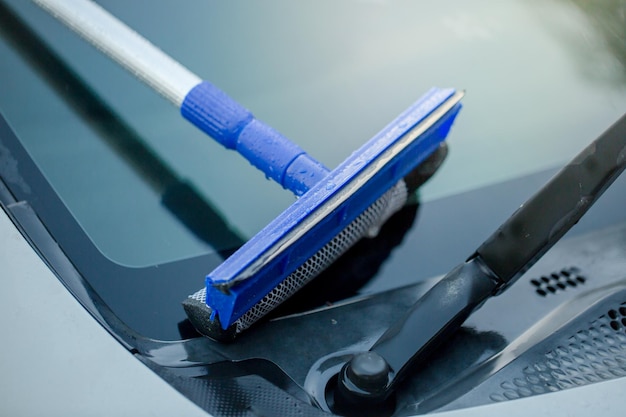 Foto close-up van een squeegee boven de voorruit van een auto