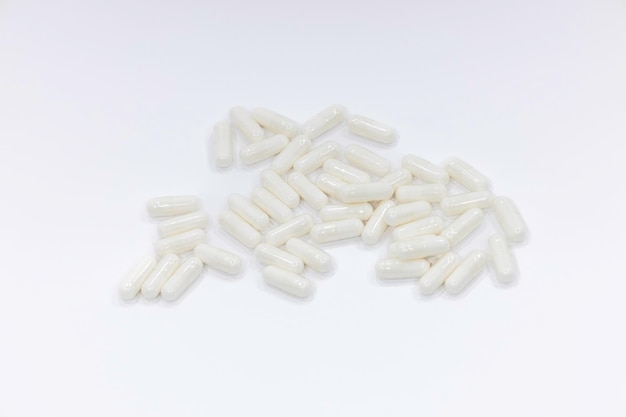 Close up van een stapel witte capsules pillen. Medicijnen op witte achtergrond.