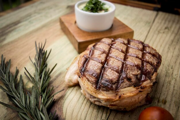 Foto close-up van een steak met rozemarijn op een houten tafel