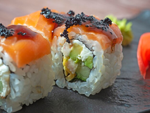 Close-up van een sushibroodje op een zwarte plaat. Traditionele Japanse keuken