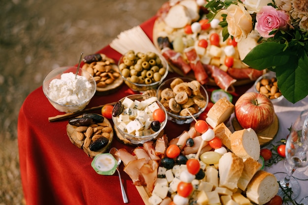 Close-up van een tafel met saladekommen met dor blauwe kaasolijven en amandelen op een rood tafelkleed