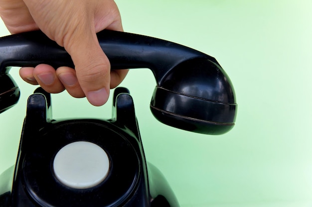 Close-up van een telefoonontvanger in de hand tegen een groene achtergrond