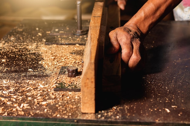 Close-up van een timmerman die een cirkelzaag of een gereedschap gebruikt om houten planken te zagen. Om meubels te maken in huizen en woningen, hotels, kamers van hout.